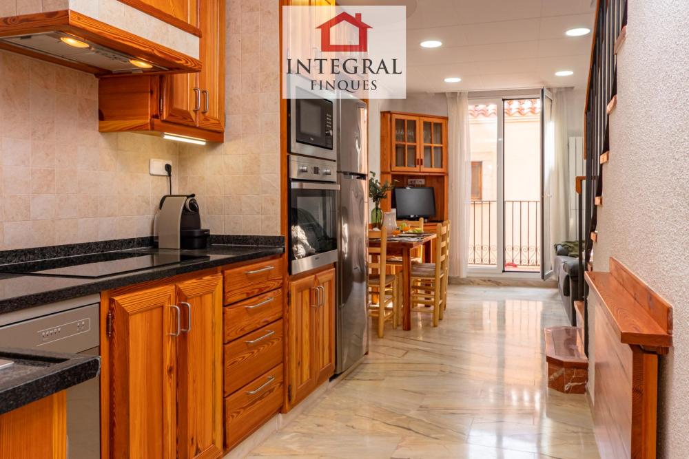 Cuina i sala d'estar amb TV i un petit balcó.