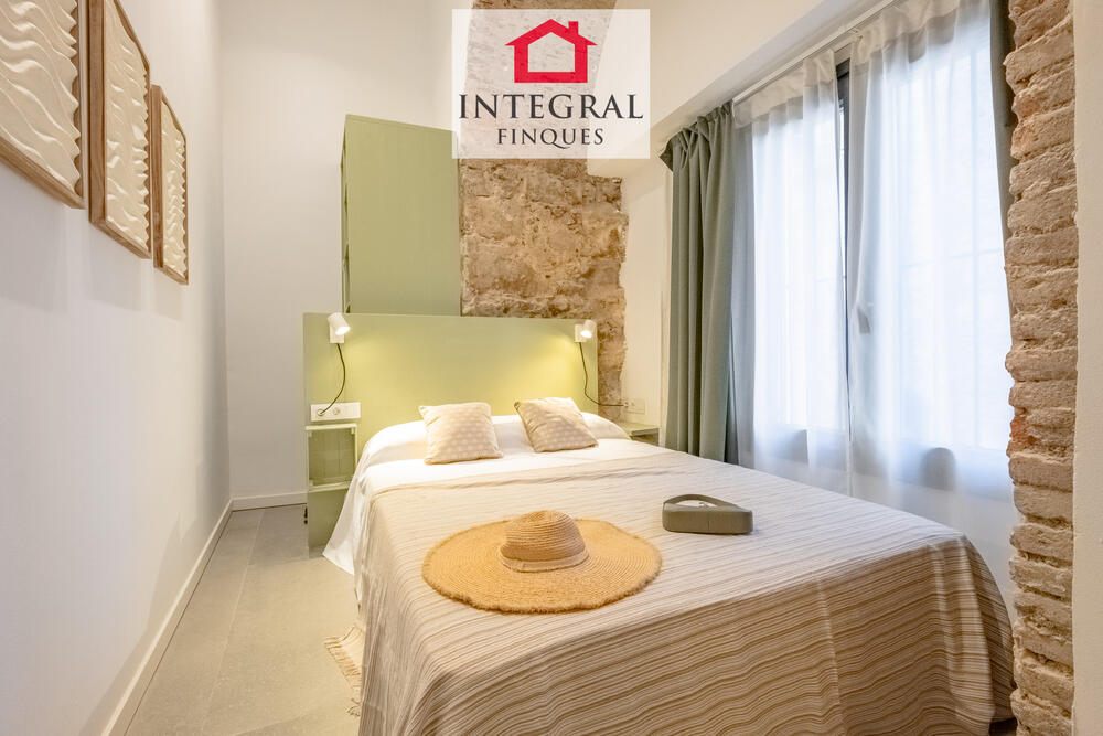 Dormitori acollidor amb llum natural, paret de pedra vista i una decoració càlida que convida al descans. Dormitori acollidor amb llum natural, paret de pedra vista i una decoració càlida que convida al descans.