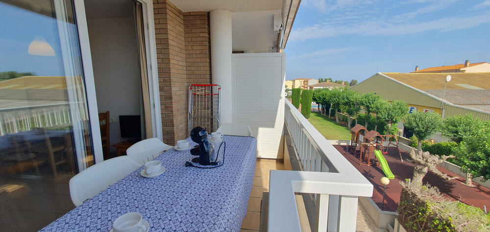 Terrasse mit Tisch und Terrassenstühlen mit Blick auf den Gemeinschaftsbereich.