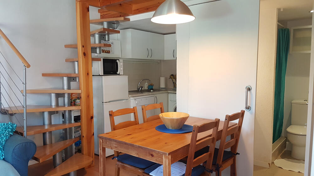 Esszimmer mit Tisch und Stühlen, daneben die Küche