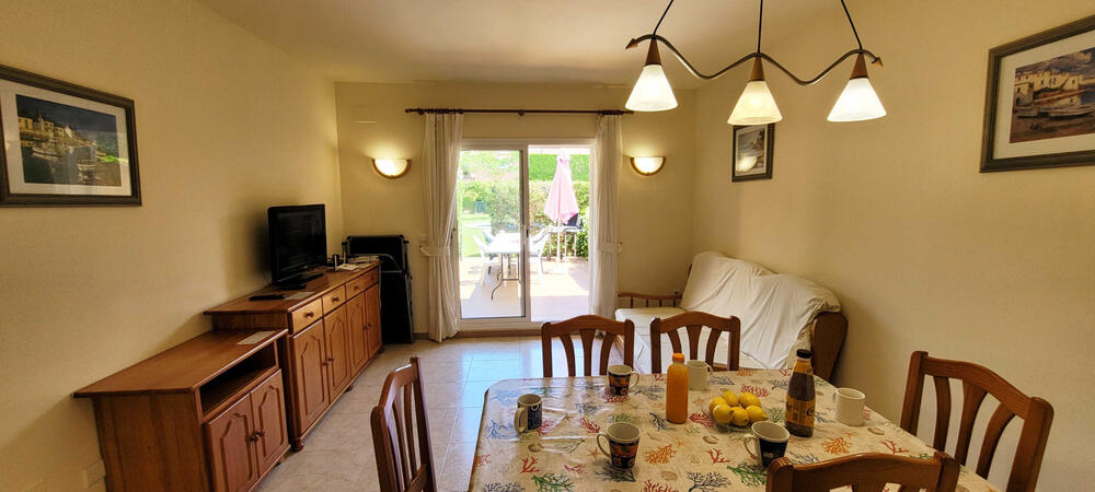 Wohnzimmer mit Sofa, Fernseher und Tisch mit Stühlen