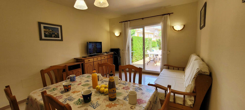Wohnzimmer mit Sofa, Fernseher und Tisch mit Stühlen