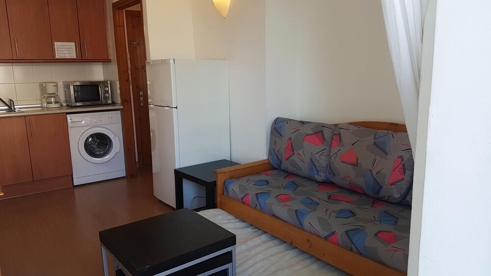 Wohnzimmer mit Sofa, Fernseher und Essbereich