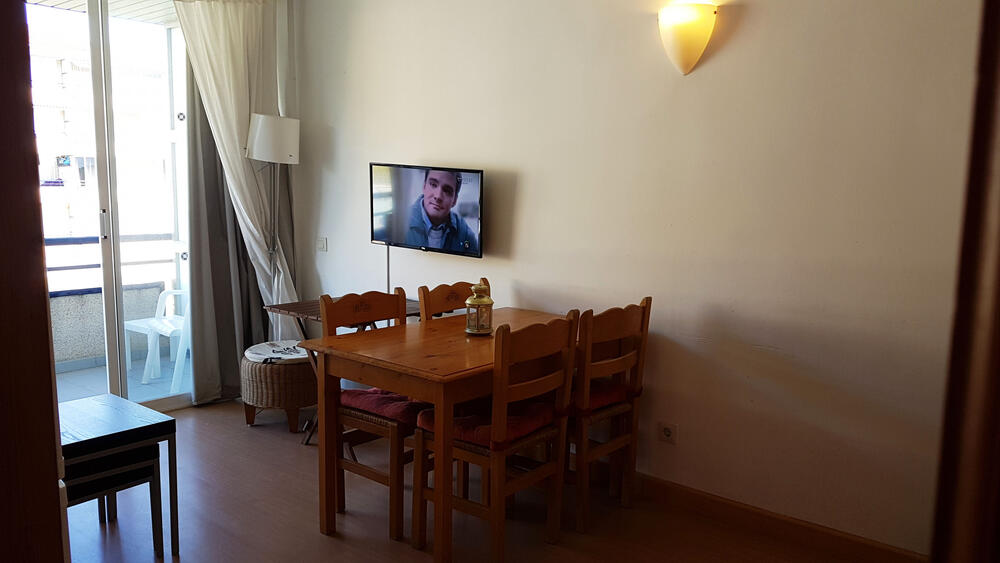Wohnzimmer mit Sofa, Fernseher und Essbereich